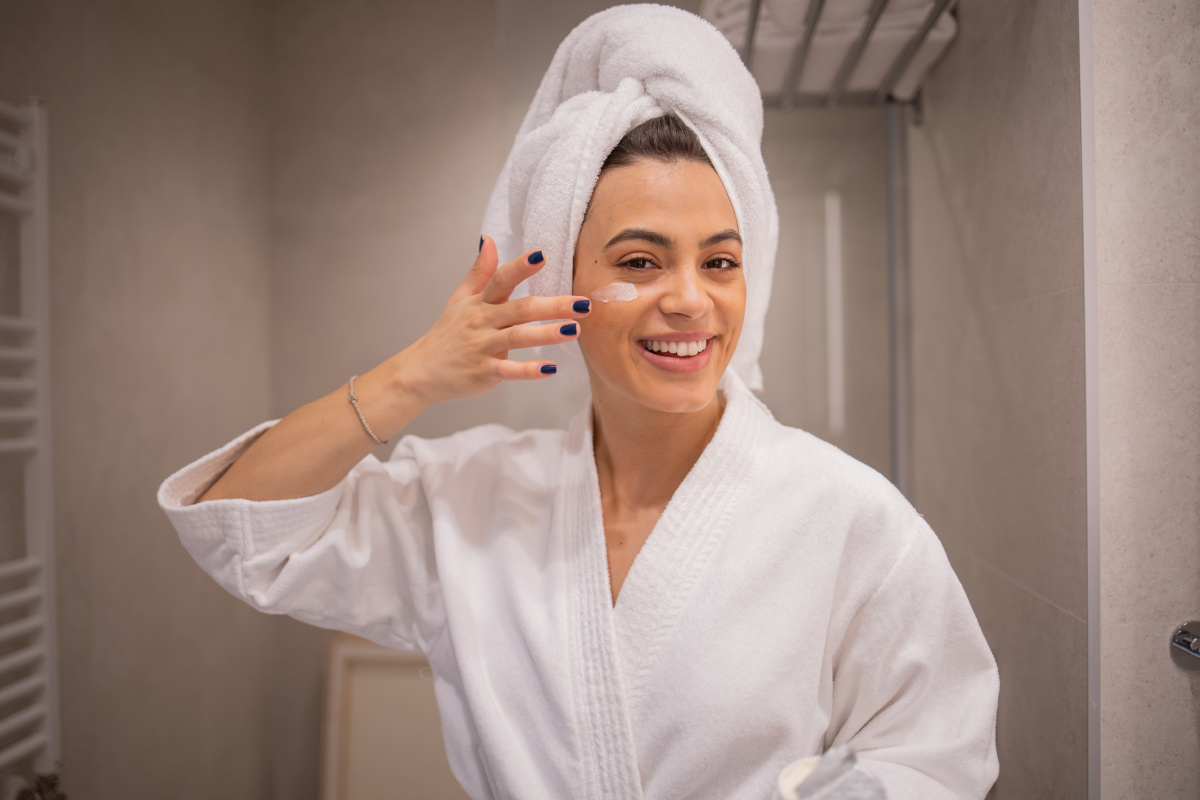 Woman smiling while applying her skincare products during the winter