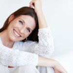 Mature woman dressed in white smiling and sitting casually