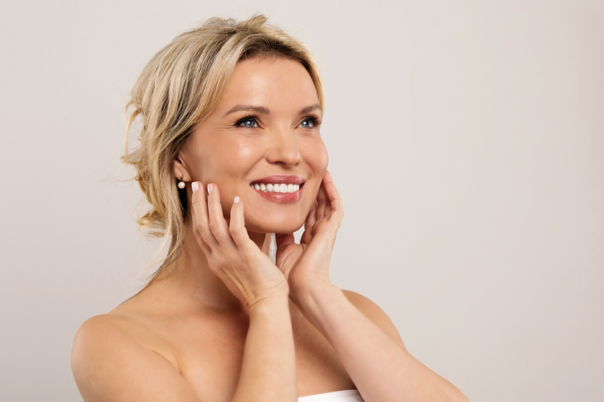 Mature 40s woman touching face and smiling off camera