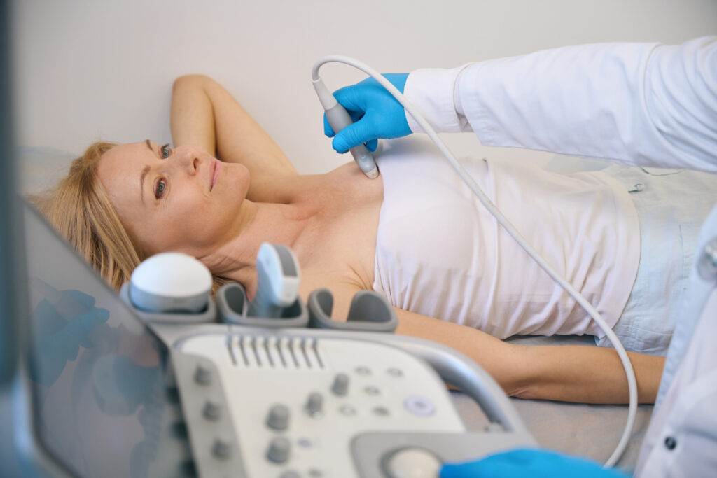 Woman undergoing routine breast implant monitoring ultrasound