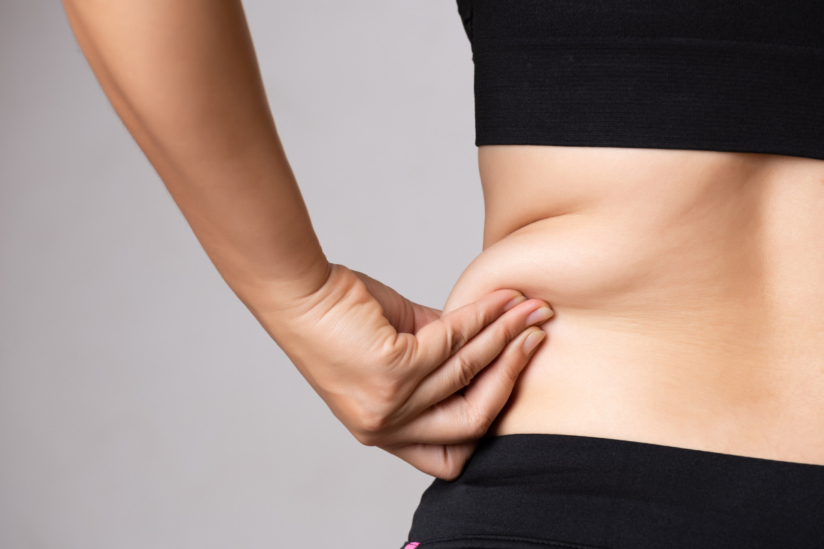 Woman pinching stubborn fat on abdomen